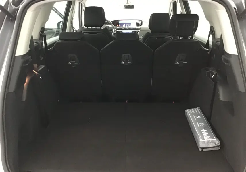 Coffre spacieux du Citroën Grand C4 Spacetourer gris Artense vu de l'arrière, avec sièges arrière relevés et kit de sécurité.