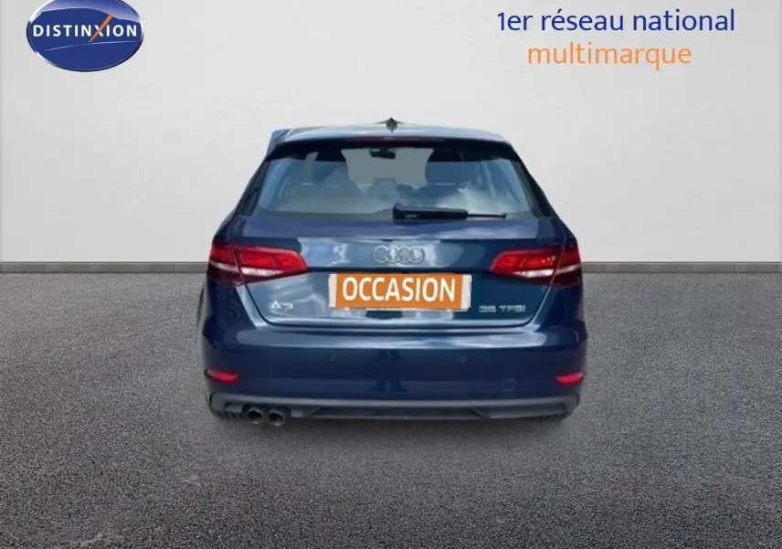 Vue arrière d'une Audi A3 Sportback bleu cosmos métal avec double sortie d'échappement et plaque "OCCASION" visible.