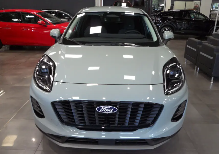 Vue frontale d'un Ford Puma gris Cactus 2025 avec calandre noire et phares LED distinctifs en showroom.