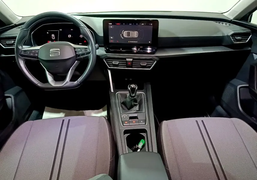 Intérieur de la SEAT Leon 2023, vue frontale du tableau de bord avec écran tactile et volant multifonctions noir.