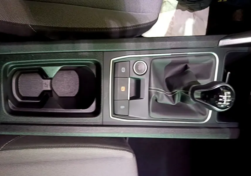 Vue plongeante sur la console centrale grise du SEAT LEON 2023, avec levier de vitesse manuel et porte-gobelets.