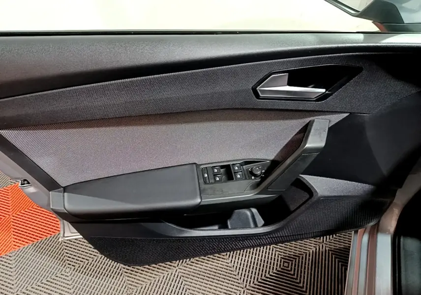 Vue rapprochée de la porte côté conducteur de la SEAT LEON gris clair, avec commandes des vitres et poignée noire.