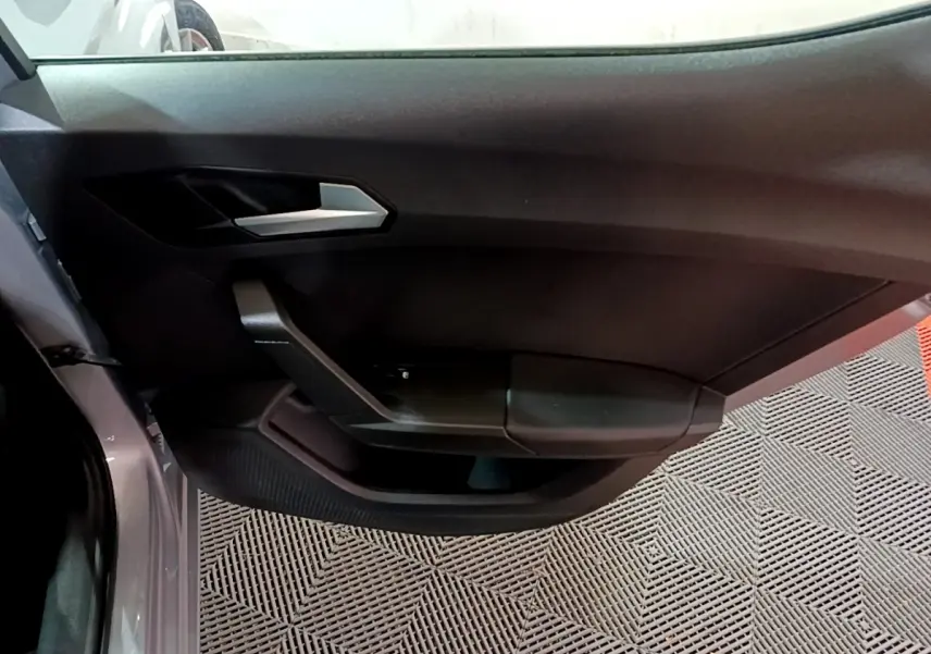 Vue rapprochée de la porte côté gauche gris clair du SEAT LEON 2023 avec poignée argentée et panneau noir mat.