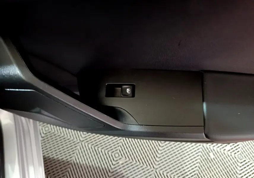 Bouton d'ouverture du coffre sur la porte côté gauche d'une SEAT Leon gris clair 2023.
