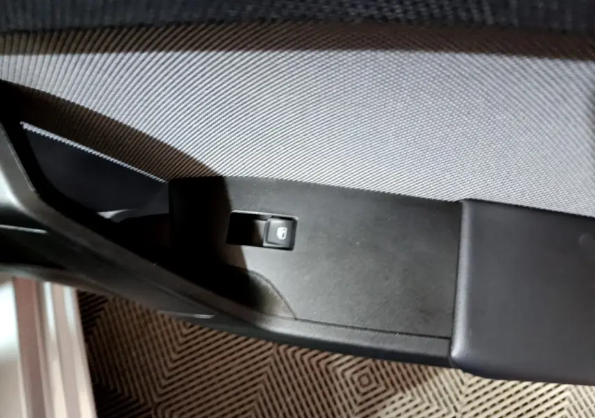 Gros plan sur le bouton de verrouillage des portes sur la garniture intérieure noire côté conducteur d'une SEAT Leon gris clair.