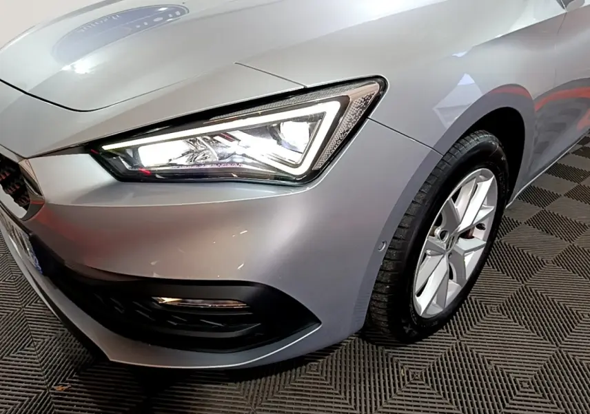 Gros plan sur l'avant droit gris clair du SEAT LEON 2023, mettant en valeur le phare LED et la jante alliage.