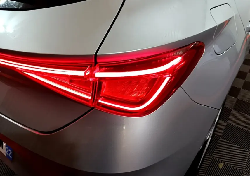 Gros plan sur le feu arrière droit rouge allumé d'une SEAT LEON gris clair 2023, avec la trappe à carburant visible.