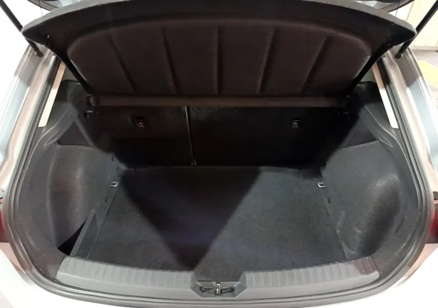 Coffre ouvert vu de l'arrière d'une SEAT LEON gris clair 2023, espace de chargement vide et tapis noir.