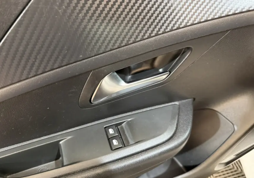 Détail de la poignée intérieure et des commandes de lève-vitres côté conducteur d’une Peugeot 208 PureTech 75 S&S Like 2020.