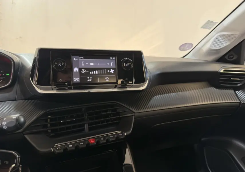 Vue intérieure du tableau de bord noir de la Peugeot 208 PureTech 75 S&S Like avec écran tactile central et commandes climatisation.