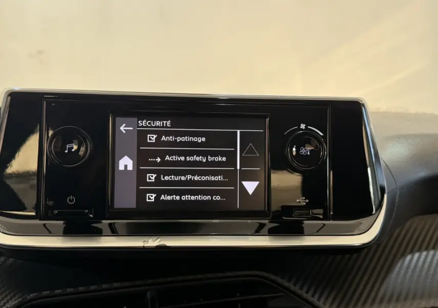 Vue rapprochée de l’écran tactile central noir de la Peugeot 208 PureTech 75 affichant les options de sécurité.
