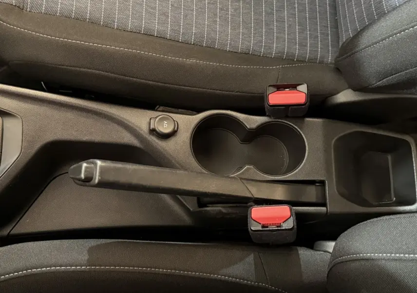 Vue rapprochée de la console centrale noire de la Peugeot 208 PureTech 75 S&S Like avec frein à main et porte-gobelets.