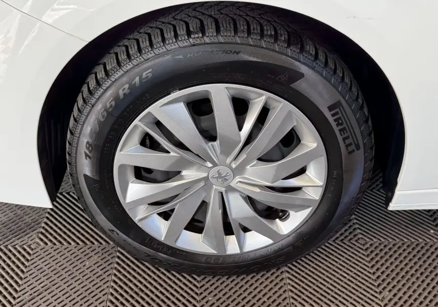 Gros plan sur la roue avant droite d’une Peugeot 208 blanche avec jante argentée et pneu Pirelli.