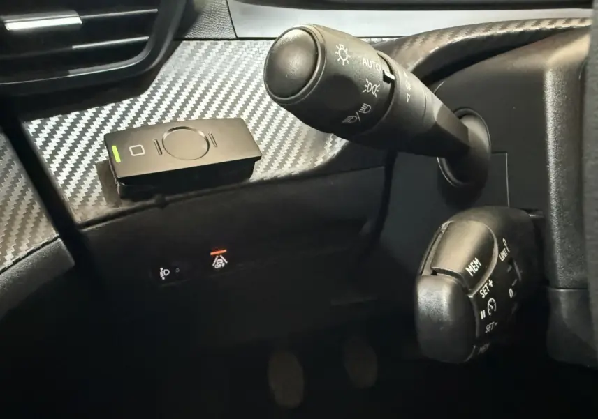 Gros plan sur la commande des feux et régulateur de vitesse du tableau de bord noir à effet carbone d'une Peugeot 208 2020.