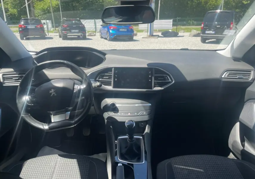 Intérieur de Peugeot 308 2020 vue de face, tableau de bord noir avec volant compact et levier de vitesse manuel.