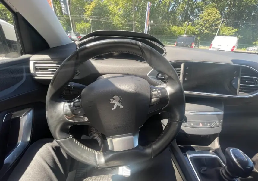 Intérieur de la Peugeot 308 2020 blanc, vue centrée sur le volant et la console avec boîte manuelle visible.