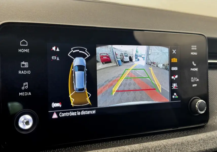 Écran tactile intérieur montrant la caméra de recul et l'aide au stationnement du Skoda Scala gris clair.