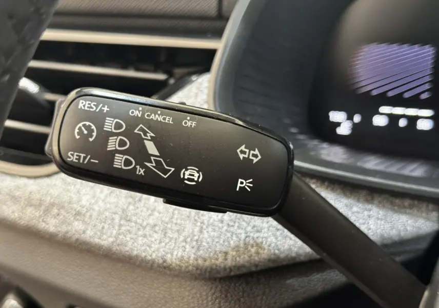 Gros plan sur la commande de régulateur de vitesse et feux, intérieur d'une Skoda Scala gris clair 2025.