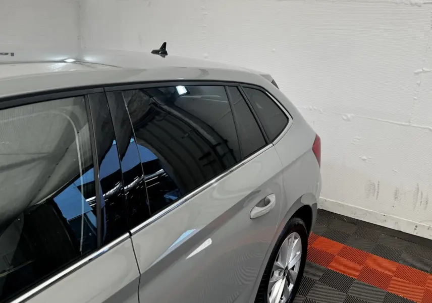 Vue 3/4 arrière côté droit d'une Skoda Scala gris clair avec vitres teintées et jantes alliage dans un garage.