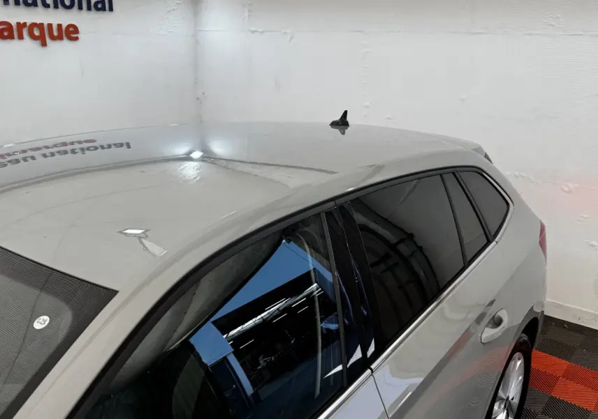 Vue 3/4 arrière droite d'une Skoda Scala gris clair avec vitres teintées et jantes argentées dans un showroom.