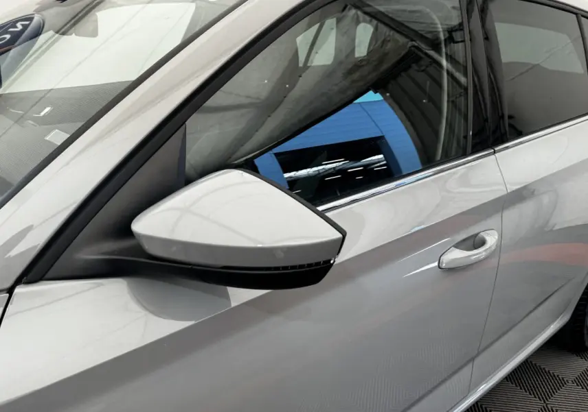 Vue rapprochée du rétroviseur et de la porte côté gauche d'une Skoda Scala gris clair 2025.