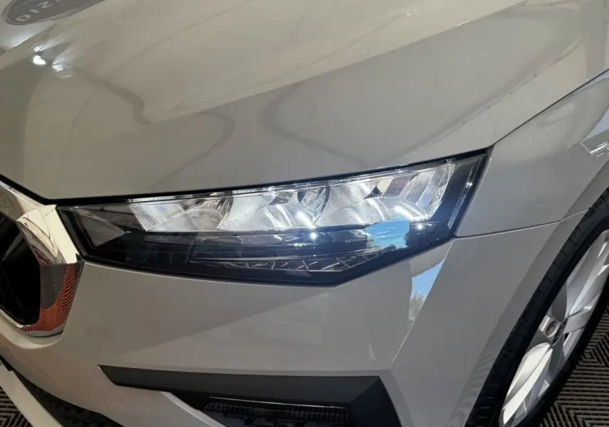 Gros plan sur le phare avant droit gris clair d'une Skoda Scala 2025, mettant en valeur les lignes nettes et la calandre chromée.