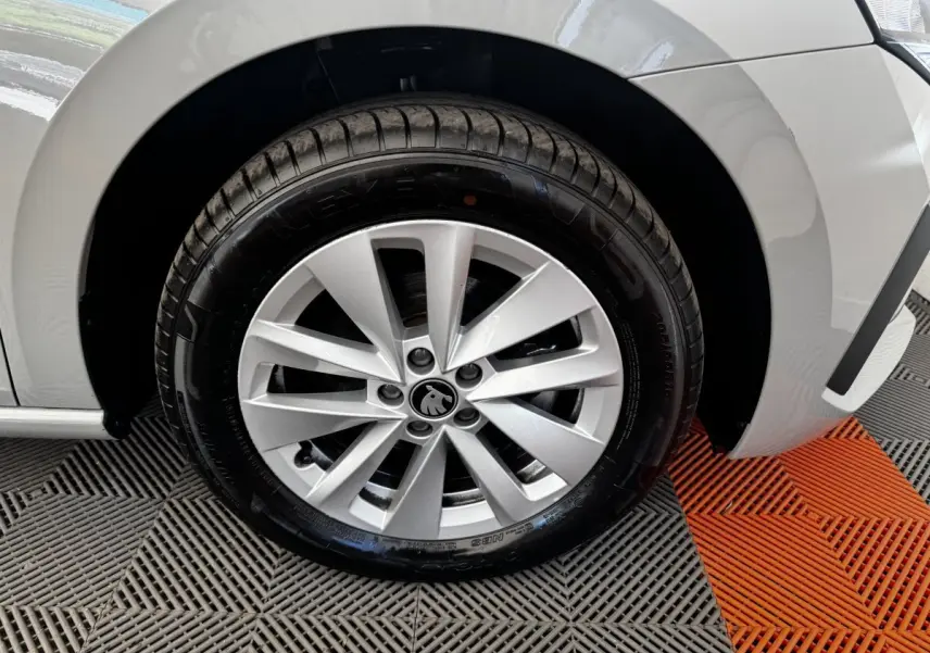 Gros plan sur la roue avant droite gris clair d'une Skoda Scala 2025 avec jante alliage et logo central visible.