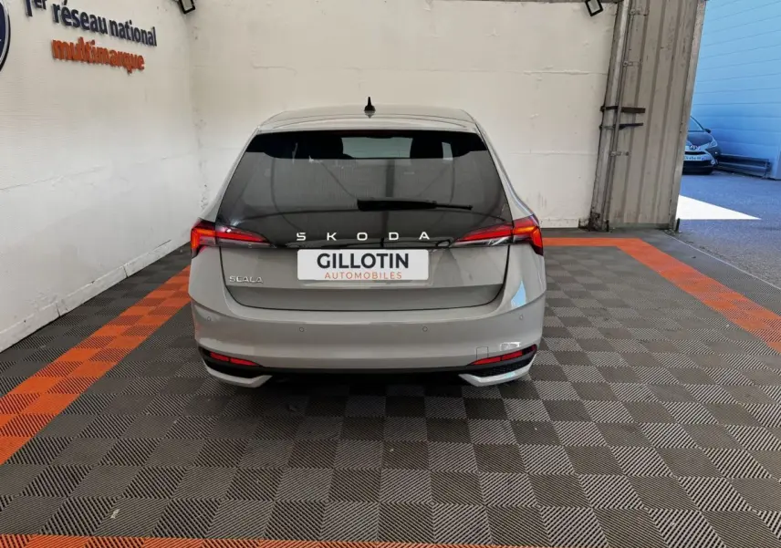 Vue arrière d'une Skoda Scala gris clair 2025 dans un garage avec éclairage naturel à droite.