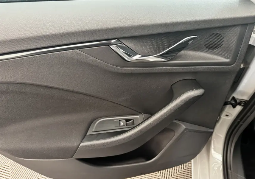 Vue intérieure de la porte avant droite d'une Skoda Scala gris clair, avec poignée chromée et commande de verrouillage.