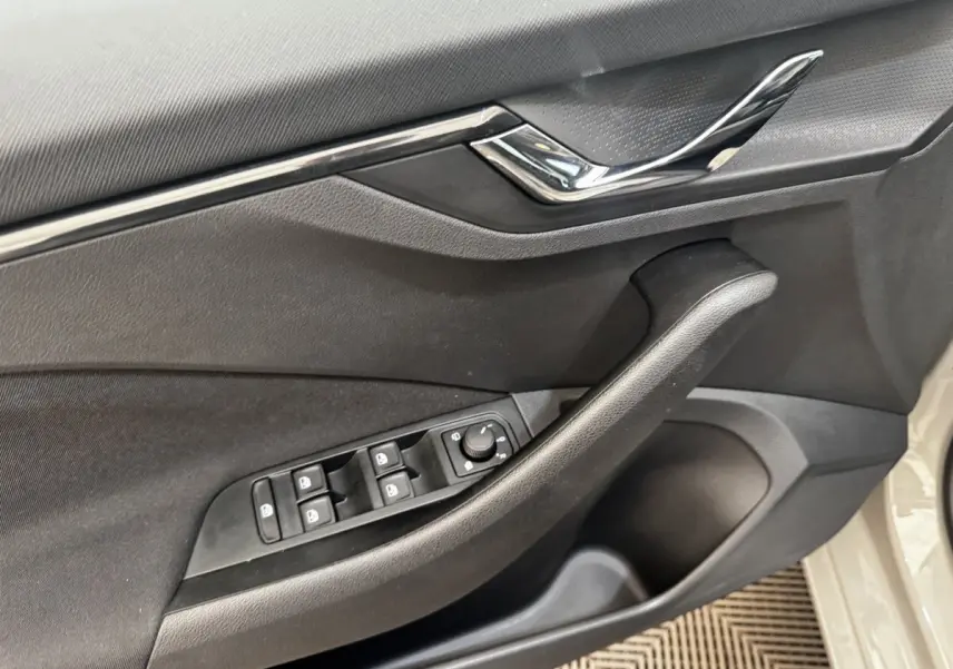 Vue rapprochée de la porte côté conducteur d'une Skoda Scala gris clair, avec commandes des vitres et miroir.