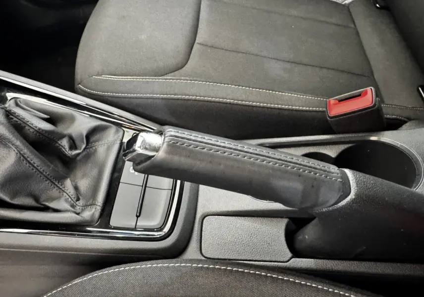Gros plan intérieur sur le frein à main en cuir noir et la console centrale d’une Skoda Scala gris clair.