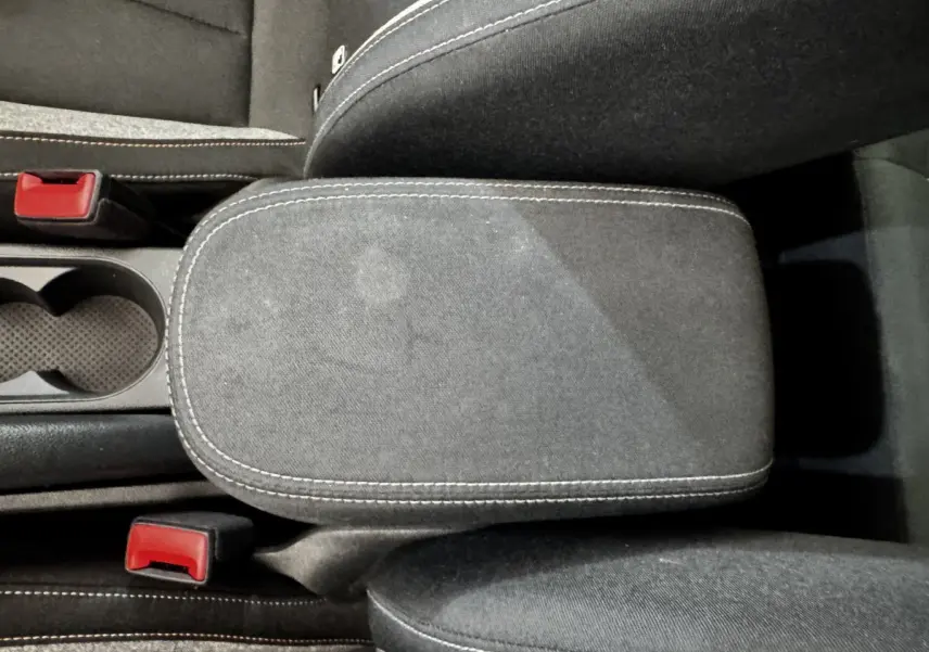 Vue rapprochée de l'accoudoir central gris foncé avec surpiqûres blanches et porte-gobelets d'une Skoda Scala 2025.