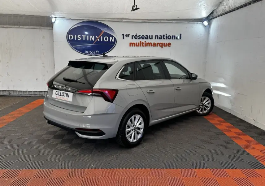 Vue 3/4 arrière droite d'une Skoda Scala gris clair dans un showroom avec feux arrière LED et jantes alliage.