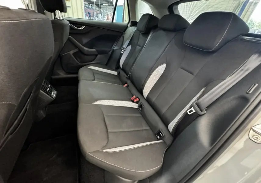 Vue intérieure arrière droite de la Skoda Scala 2025 gris clair, montrant la banquette tissu noire avec inserts gris clair.