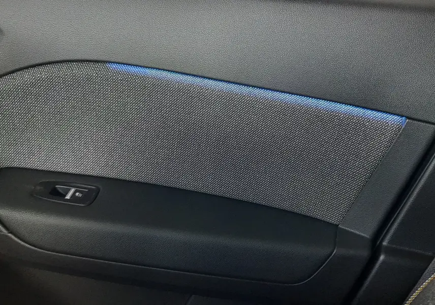 Gros plan sur la garniture intérieure de porte côté droit du Renault Captur E-Tech Hybrid bleu iron avec bandeau lumineux bleu.