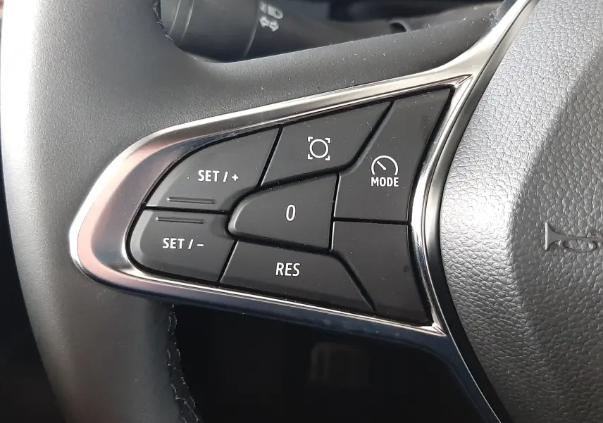 Gros plan sur les commandes de régulateur de vitesse au volant du Renault Captur E-Tech Hybrid 2024, intérieur noir.