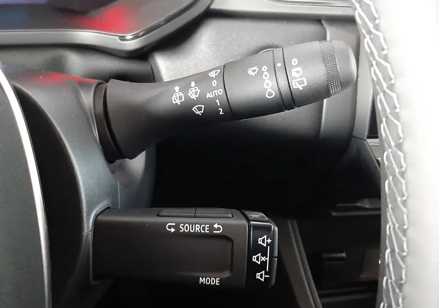 Gros plan sur les commandes de volant du Renault Captur E-Tech Hybrid 2024, avec boutons source et essuie-glace visibles.