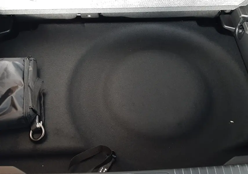 Coffre arrière du Renault Captur E-Tech Hybrid 2024, vue plongeante sur le rangement noir avec sac de secours.