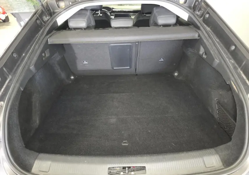 Coffre ouvert vu de l'arrière d'une Peugeot 508 gris, montrant l'espace de chargement et la banquette arrière.