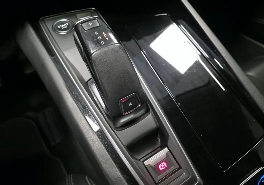 Gros plan sur la console centrale noire brillante de la Peugeot 508 gris, avec levier de vitesse automatique et frein à main électrique.