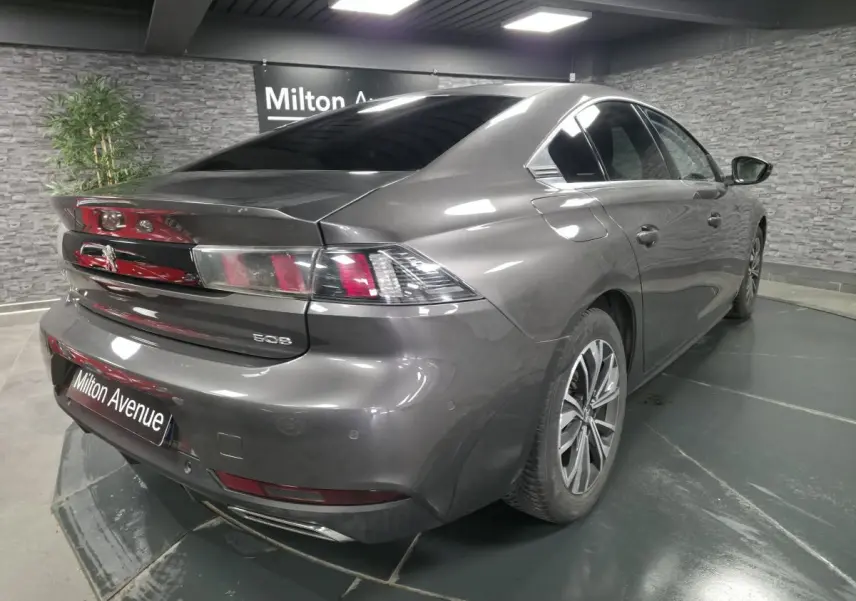 Peugeot 508 gris métallisé vue 3/4 arrière droit en intérieur avec jantes alliage et double échappement chromé.