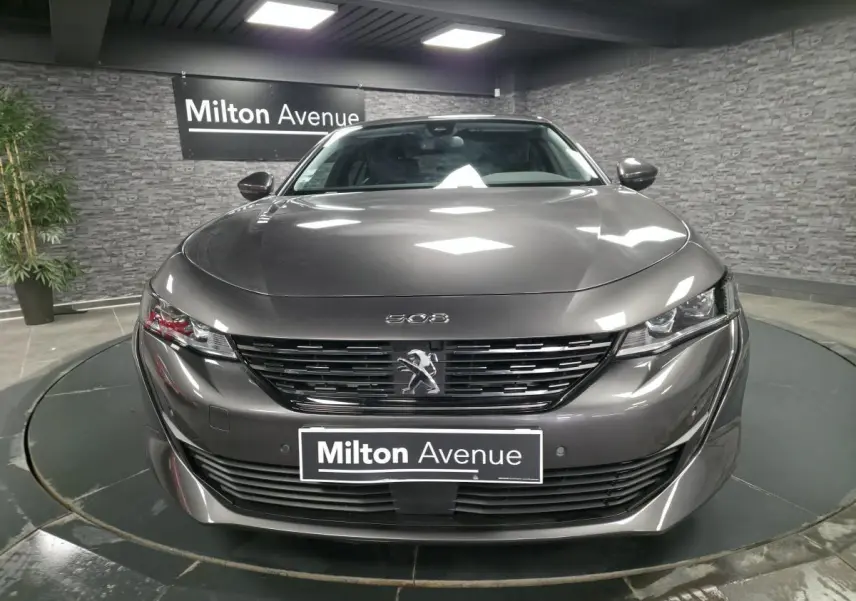 Peugeot 508 gris métallisé vue de face avec calandre noire et logo lion au centre, en showroom.