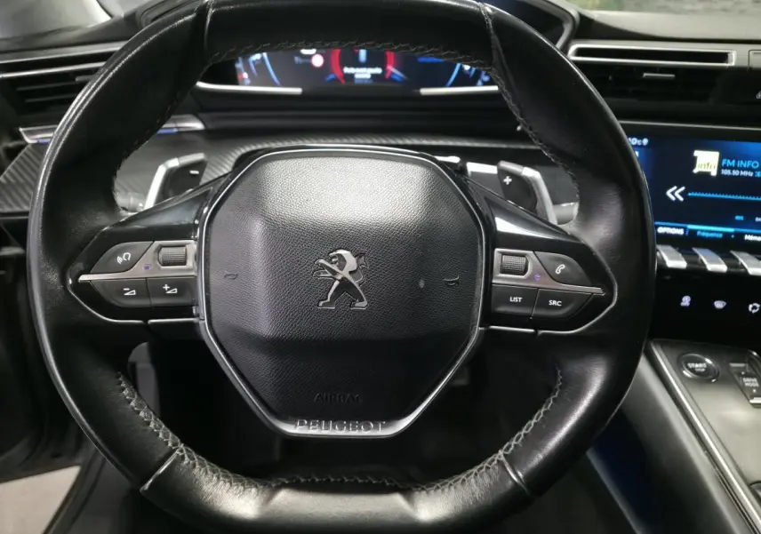 Volant cuir noir Peugeot 508 2018 avec commandes intégrées et tableau de bord numérique en arrière-plan.