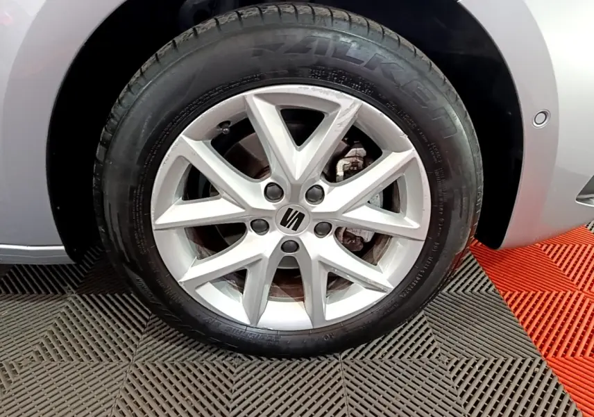 Gros plan sur la roue avant droite gris foncé d'une SEAT LEON 2023 avec jante alliage à 5 branches doubles.