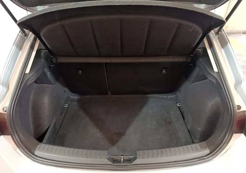 Coffre ouvert vu de l'arrière d'une SEAT Leon gris foncé, montrant un espace de chargement propre et spacieux.
