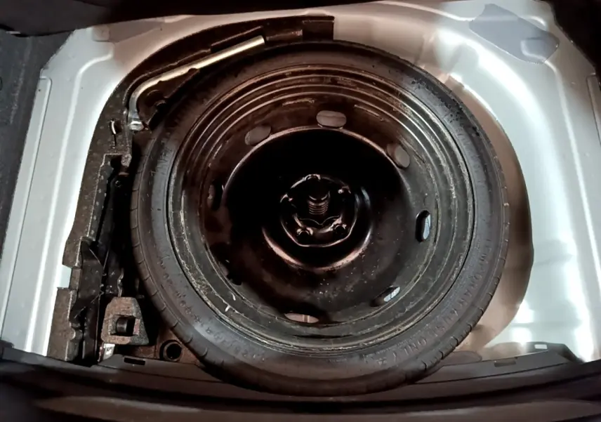 Roue de secours galette noire dans le coffre blanc d'une SEAT LEON 1.0 TSI 110 S&S Business 2023.