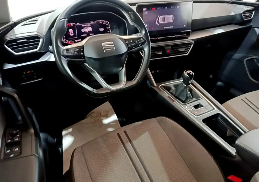 Vue intérieure côté conducteur du tableau de bord et console centrale de la SEAT LEON 1.0 TSI 110 S&S Business 2023 en gris foncé.