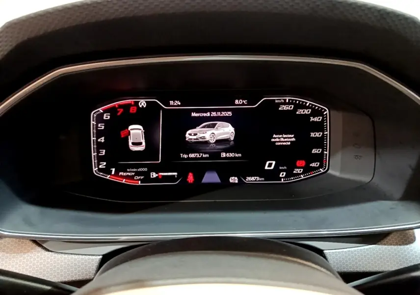 Vue rapprochée du tableau de bord numérique de la SEAT LEON 2023 affichant vitesse, compte-tours et image du véhicule gris foncé.