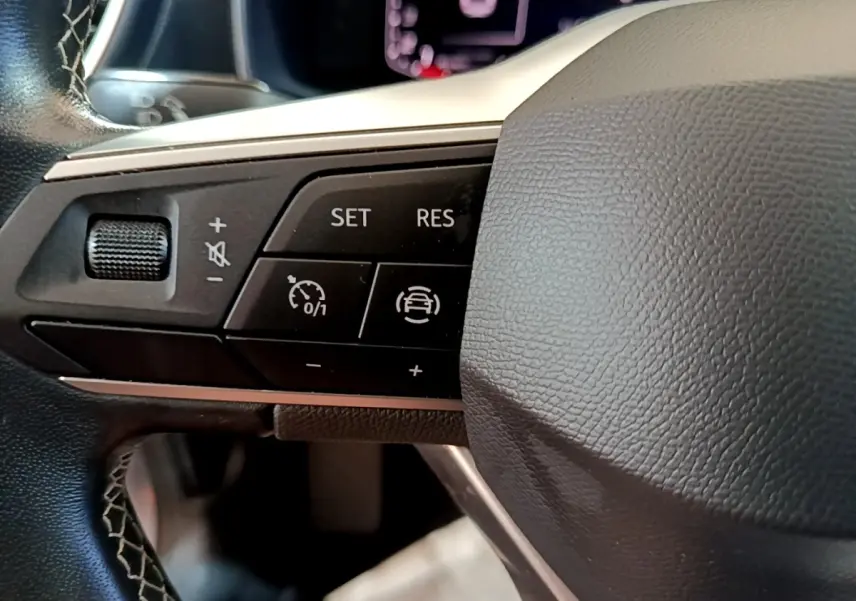 Gros plan sur les commandes de régulateur de vitesse au volant cuir noir du SEAT Leon gris foncé 2023.