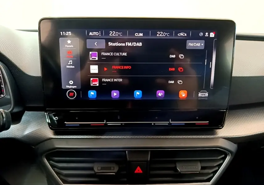 Écran tactile central affichant les stations FM/DAB dans l'habitacle du SEAT Leon gris foncé de 2023.